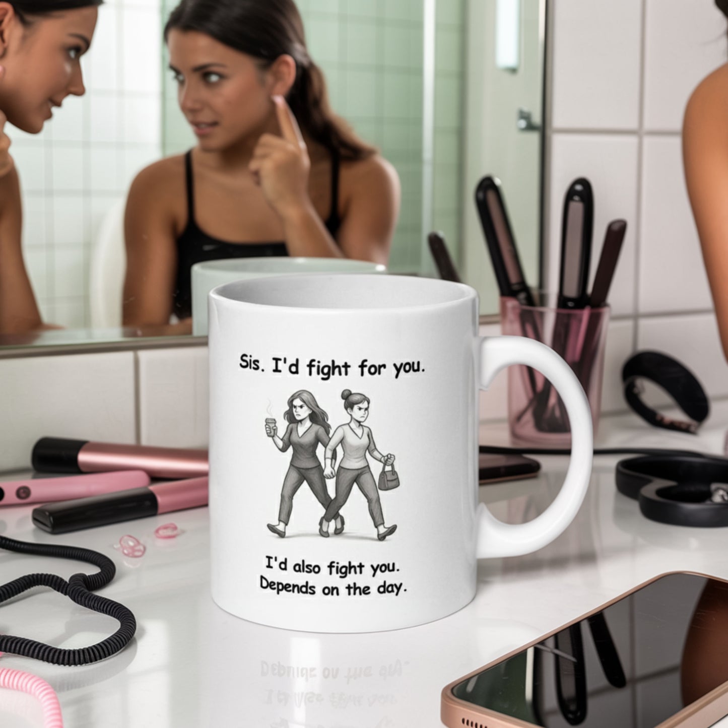 A humorous white mug with a black-and-white cartoon of two sisters walking side by side; one holds a coffee, the other a purse. The mug reads, “Sis. I’d fight for you. I’d also fight you. Depends on the day.” It's placed on a cluttered bathroom vanity with makeup tools and a phone, while a woman looks at her sister in the mirror, mid-conversation, suggesting a relatable sister moment.
